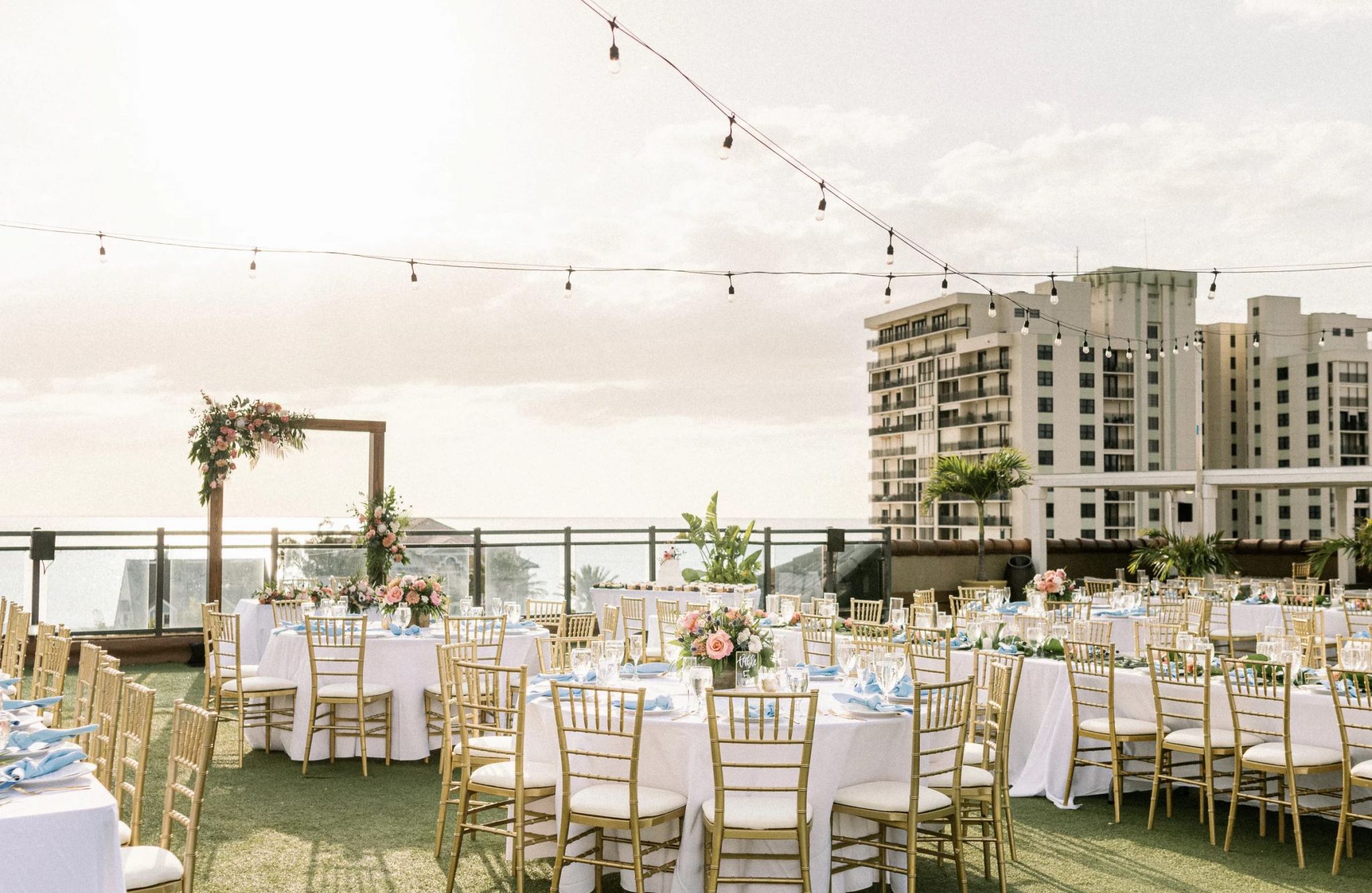 Gulfside rooftop space with chairs, a beautiful view, and tables, available for booking events or meetings